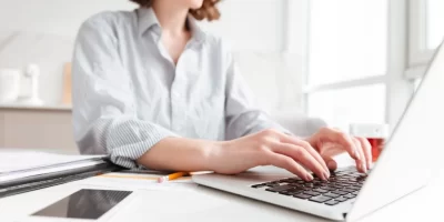 brunette-woman-typing-email-on-laptop-computer-while-sitting-at-home-selective-focus-on-hand