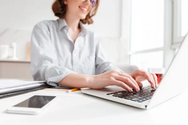 brunette-woman-typing-email-on-laptop-computer-while-sitting-at-home-selective-focus-on-hand